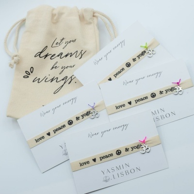 Pulseiras bege com texto love peace yoga, pingente prateado e bolsa de tecido com frase inspiradora