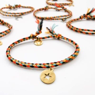 Pulseiras trançadas coloridas com pendentes dourados em fundo branco