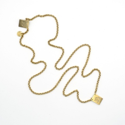 Colar dourado com pendentes gravados em fundo branco