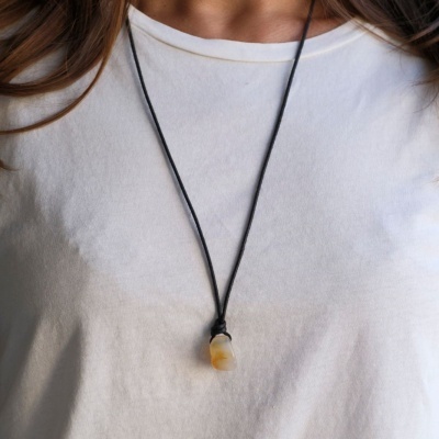 Colar com pendente em pedra amarela em cordão preto sobre t-shirt branca