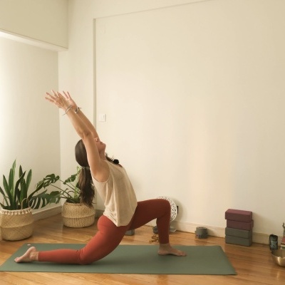 Pessoa a praticar yoga num tapete verde numa sala com chão de madeira e plantas