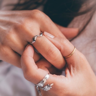 Mão com anel de prata ondulado e outros anéis decorativos