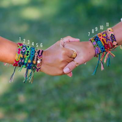 Mãos com pulseiras trançadas coloridas numeradas de 1 a 11 com fundo de relva verde