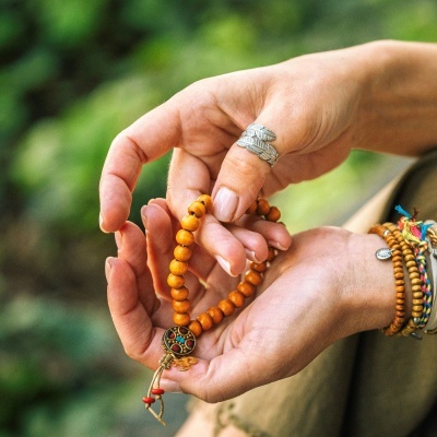 pulseira mala de contas de madeira castanha com pendente colorido nas mãos