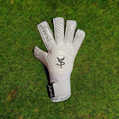 Luva de guarda-redes branca com logótipos pretos sobre relva