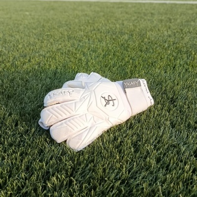 Luva branca de guarda-redes sobre relva de campo de futebol