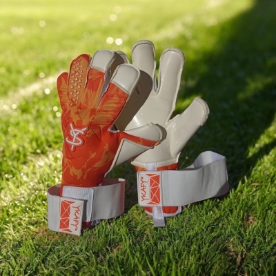 Luvas de guarda-redes de futebol laranja e branco com a marca YAAFY na relva