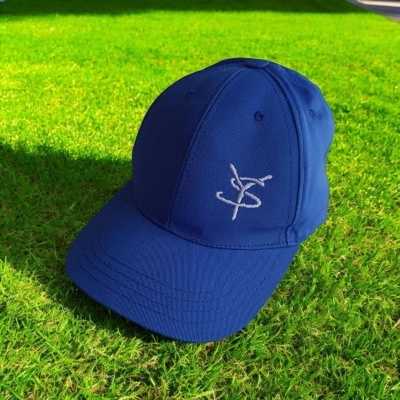 Boné azul escuro com bordado branco sobre relva verde