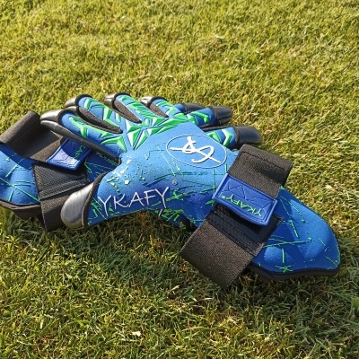 Par de luvas desportivas azuis e verdes com velcro na relva