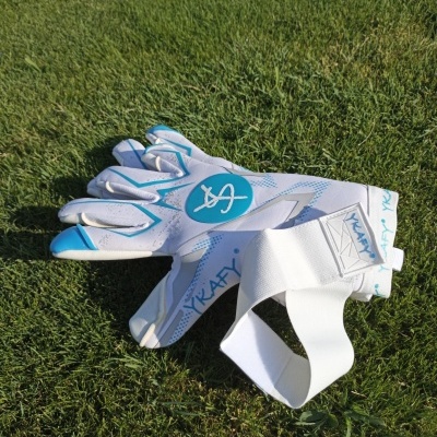 Luvas desportivas brancas e azuis sobre relvado verde