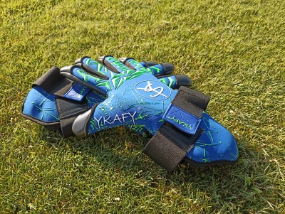 Par de luvas desportivas azuis e verdes com velcro na relva