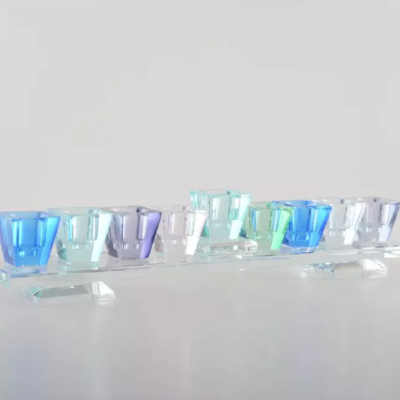 Conjunto de 9 castiçais coloridos em vidro sobre suporte transparente.