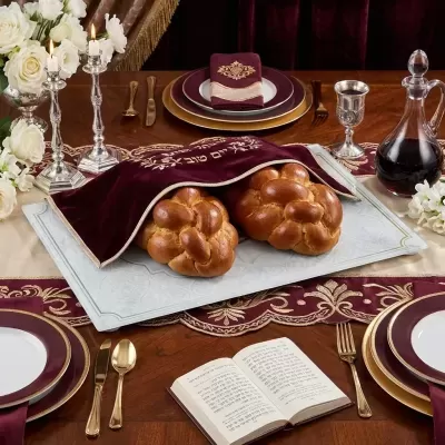 Mesa de jantar decorada com pão trançado e itens festivos em tom vinho e dourado