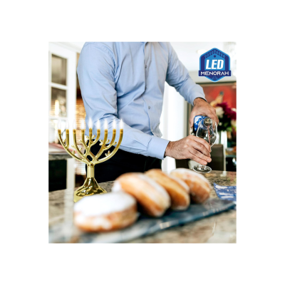 Menorá LED dourada com nove velas numa cozinha com homem a servir bebida em copo e sonhos em primeiro plano