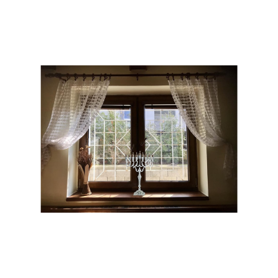 Janela com cortinas brancas e castiçal no peitoril