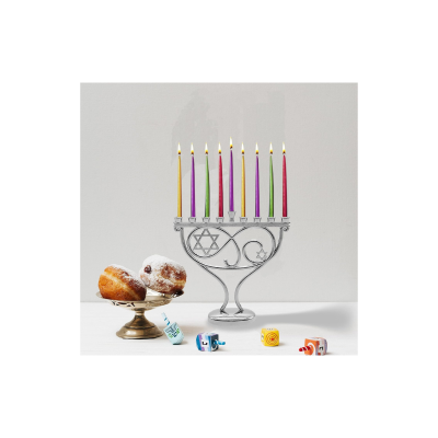 Candelabro de Chanucá com velas acesas, bolos e dreidels coloridos sobre superfície branca