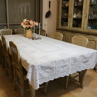 Mesa de jantar com toalha branca rendada e cadeiras de madeira