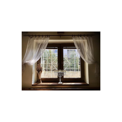 Janela de madeira com cortinas brancas transparentes e decoração com vaso e castiçal.