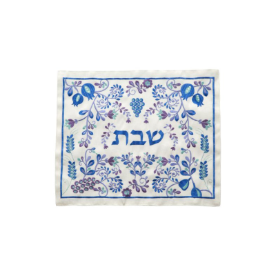 Toalha de mesa branca com padrão decorativo azul e roxo e texto hebraico.