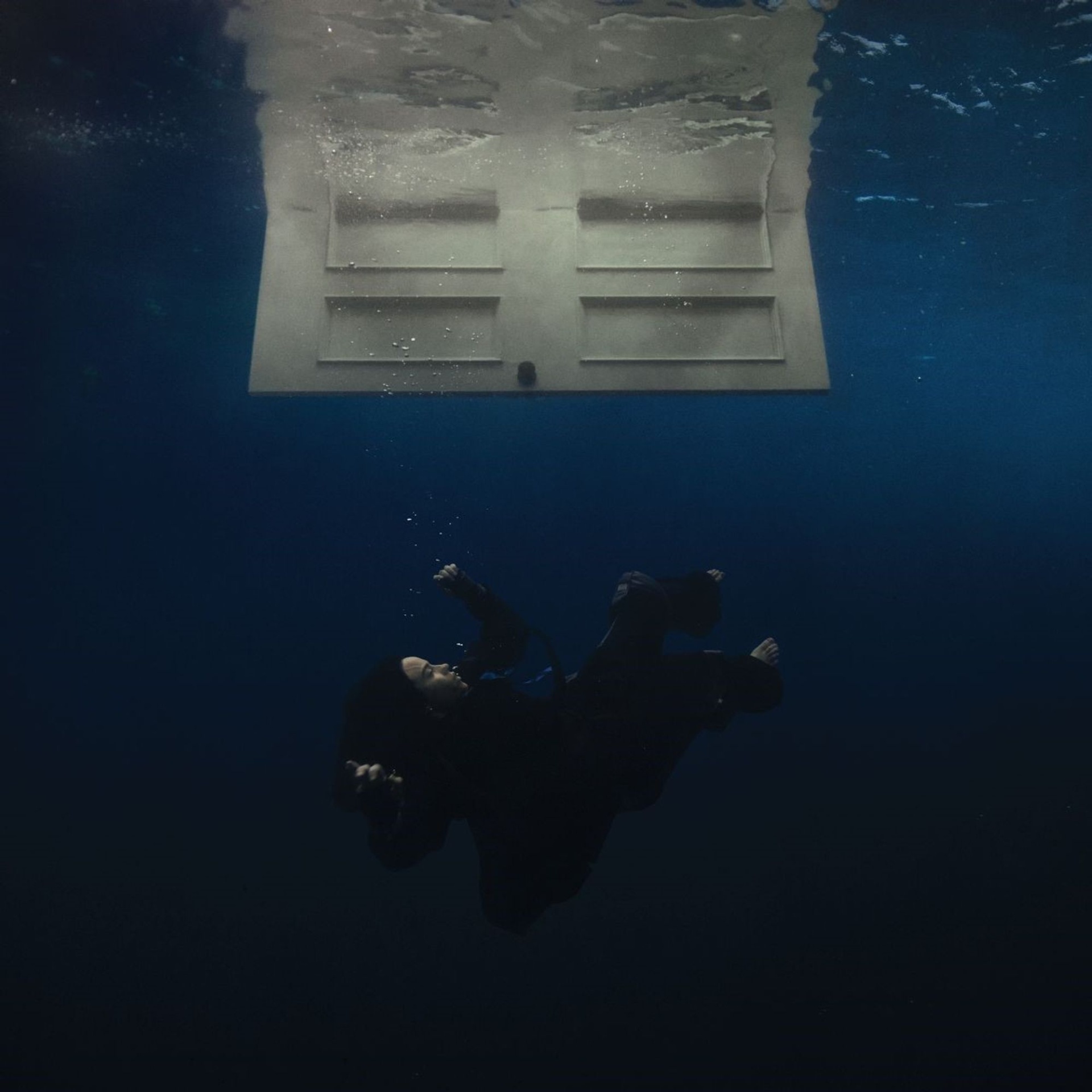 Billie Eilish - Hit Me Hard And Soft Pessoa com roupa de mergulho azul escuro sob a água perto de uma estrutura branca