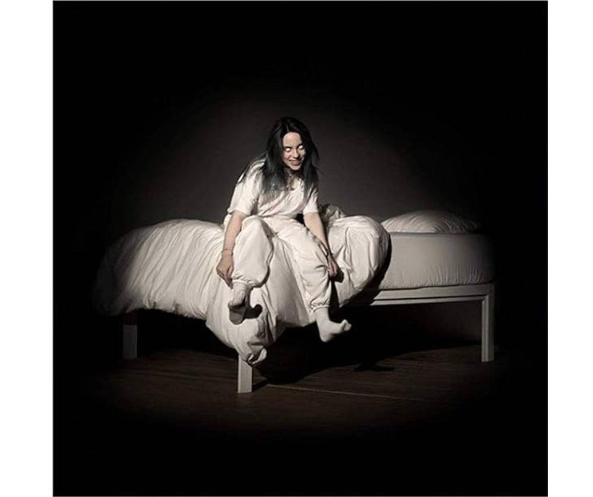 Billie Eilish - When We All Fall Asleep, Where Do We Go? (Pale Yellow Vinyl) Pessoa sentada numa cama branca com roupa de cama branca num ambiente escuro