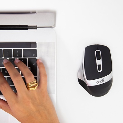 Mão a digitar num portátil com rato ao lado sobre mesa branca