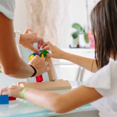 Jogo de encaixe de madeira colorida em mesa de vidro com duas pessoas