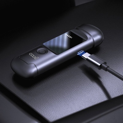 Dispositivo eletrónico preto com ecrã e botão ligado por cabo USB tipo C sobre superfície preta