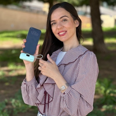 Mulher segura smartphone preto ligado a dispositivo azul com texto coco