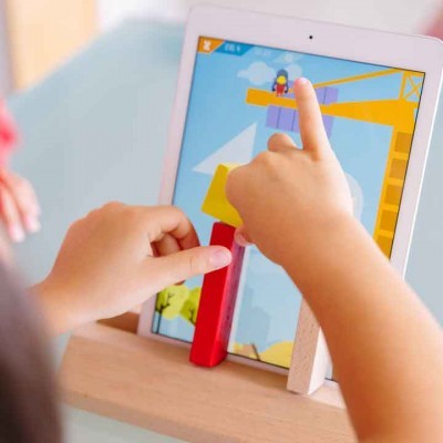 Tablet com jogo infantil e blocos de madeira com mãos de criança