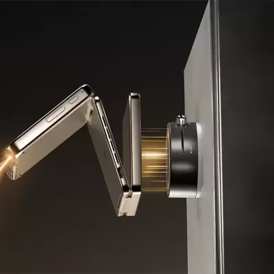 Projetor portátil dobrável dourado a emitir luz, montado numa base preta numa superfície cinza