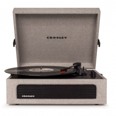Gira-discos Crosley bege com tampa aberta e vinil a tocar.