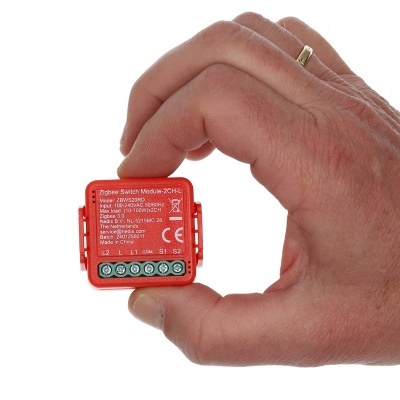 Módulo interruptor Zigbee vermelho pequeno segurado por mão humana