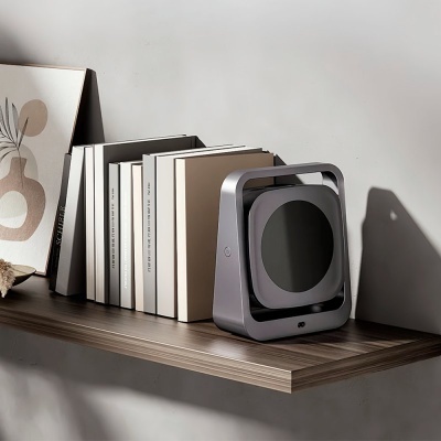 Prateleira com livros, quadro com arte abstrata e aparelho eletrônico cinza