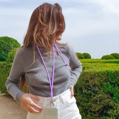 Pessoa com camisola cinza, calças brancas e sistema de identificação num jardim