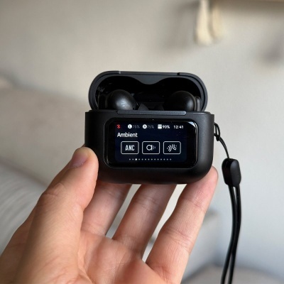 Auriculares sem fios pretos numa caixa de carregamento preta com ecrã digital mostra várias opções