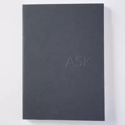 Livro ou caderno preto com texto em relevo ASK