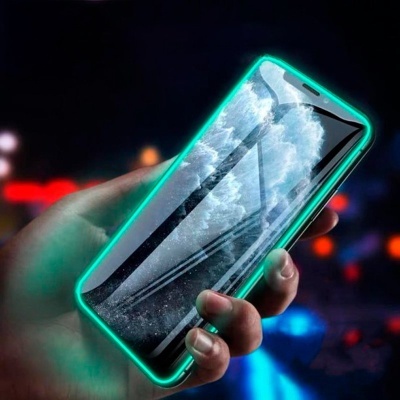 Smartphone com moldura verde neon iluminada, segurado por uma mão com fundo desfocado de luzes coloridas