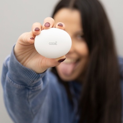Objeto oval branco com a palavra cool segurado por uma mÃ£o com unhas roxas.
