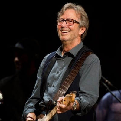 Homem a tocar guitarra elétrica num palco com fundo escuro