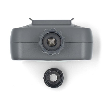 Dispositivo cinzento com lente e peça circular destacada.