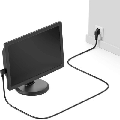 Monitor preto com cabo ligado à tomada numa parede branca.