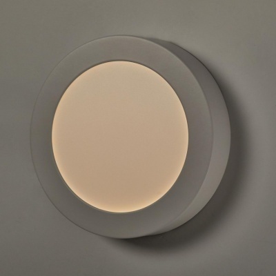 Luminária circular embutida com luz quente numa parede cinza