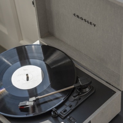 Gira-discos portátil cinza com disco vinil preto a tocar