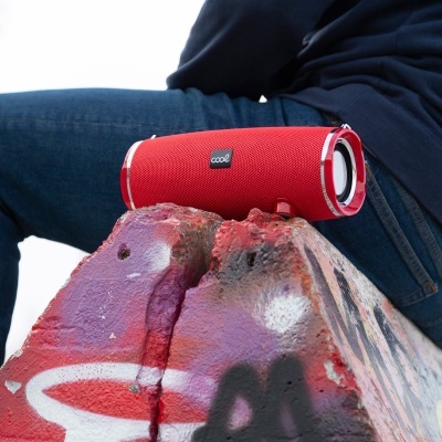 Coluna de som vermelha portátil com textura em tecido sobre pedra com graffiti