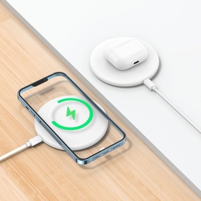 Carregadores sem fios brancos com smartphone e estojo de auriculares em superfícies clara e branca