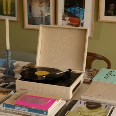 Gira-discos bege com disco preto e várias revistas e livros sobre mesa branca