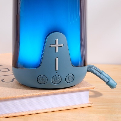 Coluna portátil azul com botões de controlo em cima de um livro