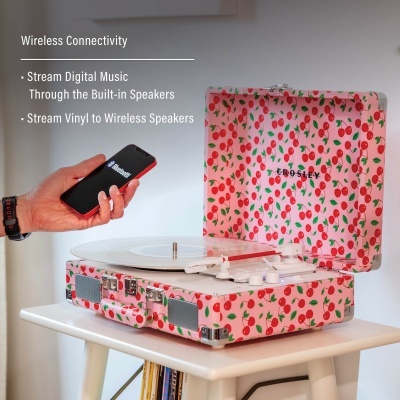 Toca-discos rosa com padrão de cerejas e um telemóvel com símbolo Bluetooth