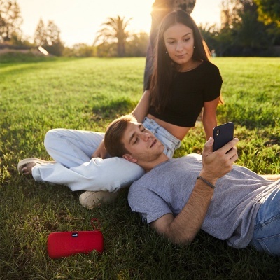Casal jovem no parque com colunas portáteis e smartphone ao pôr do sol